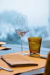 Ein Glas Wein auf einem Tisch neben einer Serviette und Besteck