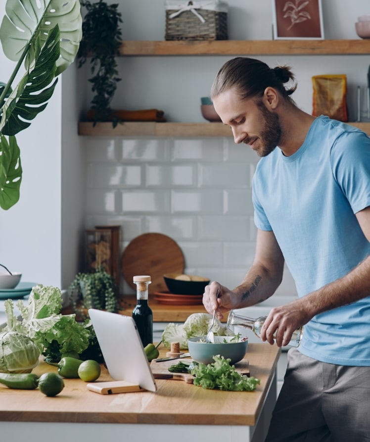 Ein Mann in einem blauen T-Shirt bereitet einen Salat zu